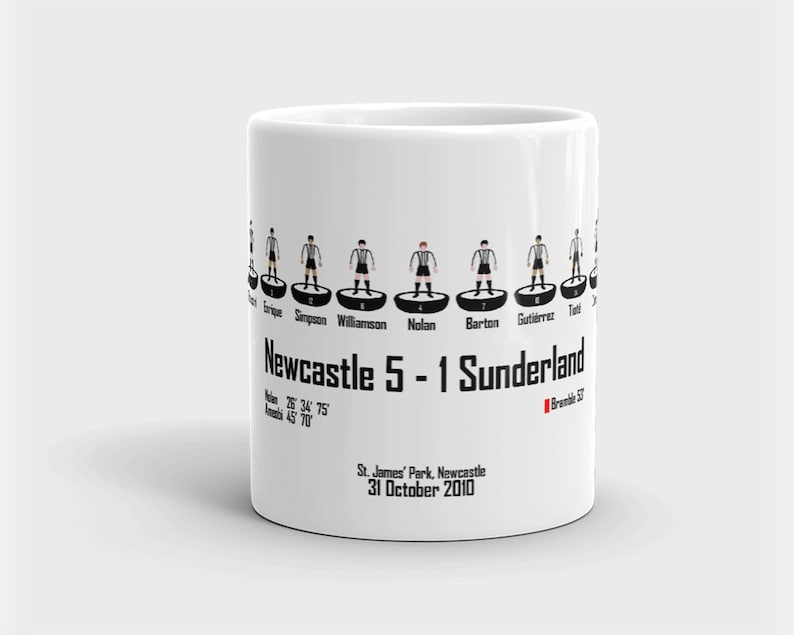 K&ouml;nnte beinhalten: Wei&szlig;e Keramiktasse mit einer Schwarzwei&szlig;illustration einer Fu&szlig;ballmannschaft. Der Text "Newcastle 5 - 1 Sunderland" ist auf der Tasse aufgedruckt, zusammen mit dem Datum "31. Oktober 2010".