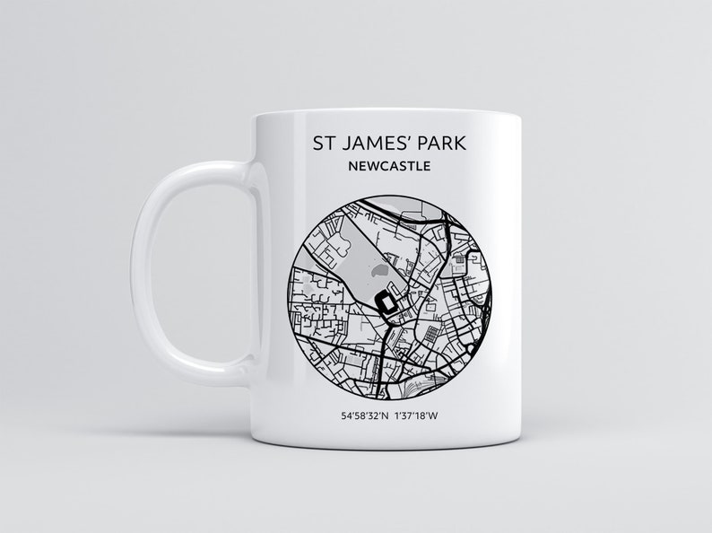 Pu&ograve; includere: Una tazza in ceramica bianca con una mappa in bianco e nero di St. James' Park, Newcastle, Inghilterra. La tazza ha il testo "St. James' Park Newcastle" e le coordinate "54&deg;58'32"N 1&deg;37'18"W" stampate su di essa.