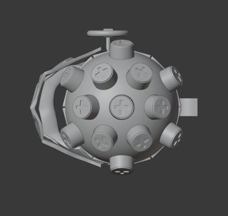 May include: A gray, round, spiky object with a handle and a small wheel on top. The object has a series of small, round, raised bumps with a plus sign on each.