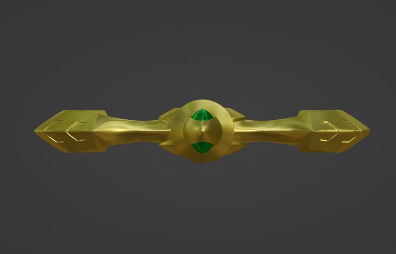 May include: A gold-colored metal decorative piece with a green gemstone in the center. The piece has a symmetrical design with two pointed ends.