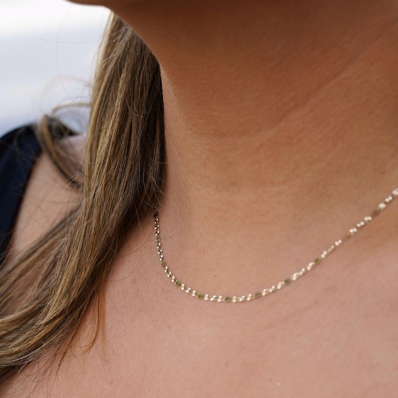 A model elegantly wearing the 14K solid gold Valentino chain necklace, showcasing its refined, lightweight design. The 2mm chain drapes gracefully around the neck, highlighting its polished gold shine. Perfect for everyday wear or special occasions, this Italian-made chain exudes timeless sophistication and versatility.