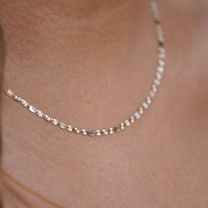 A model elegantly wearing the 14K solid gold Valentino chain necklace, showcasing its refined, lightweight design. The 2mm chain drapes gracefully around the neck, highlighting its polished gold shine. Perfect for everyday wear or special occasions, this Italian-made chain exudes timeless sophistication and versatility.