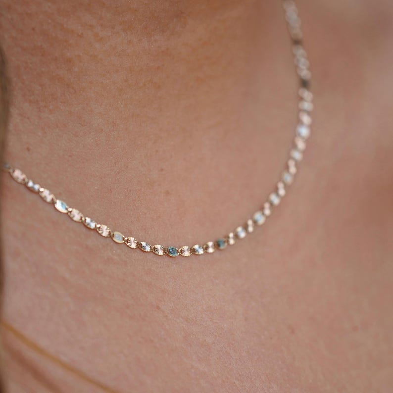 A model elegantly wearing the 14K solid gold Valentino chain necklace, showcasing its refined, lightweight design. The 2mm chain drapes gracefully around the neck, highlighting its polished gold shine. Perfect for everyday wear or special occasions, this Italian-made chain exudes timeless sophistication and versatility.