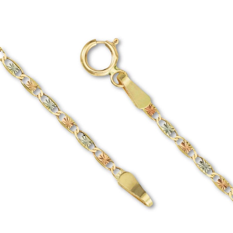 A close-up of a 14K tri-color Valentino chain laid on a plain background, showcasing its intricate links in rose, white, and yellow gold.