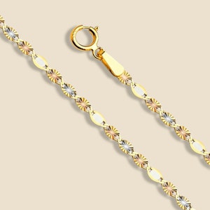 May include: A gold chain necklace with a three-tone design. The chain is made of yellow, white, and rose gold. The chain has a diamond-shaped pattern.