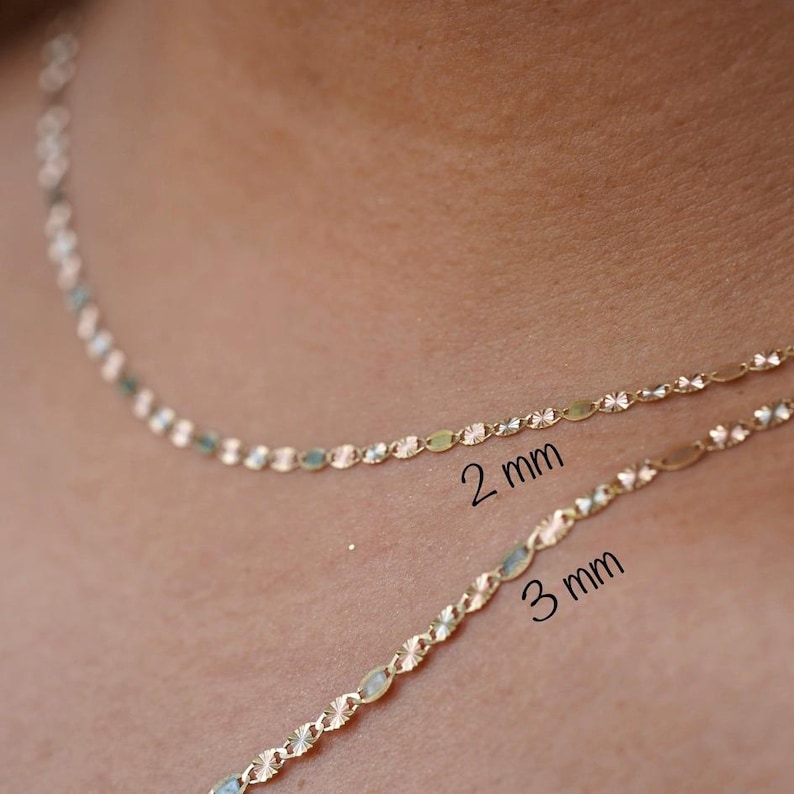 A model elegantly wears the 14K solid gold Valentino chain necklace, showcasing its refined, lightweight design. The 2mm and 3mm chains drape gracefully around the neck, highlighting their polished gold shine. Perfect for everyday wear or special occasions, these Italian-made chains exude timeless sophistication and versatility.