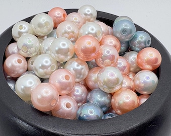 May include: A collection of iridescent beads in a black bowl. The beads are a mix of colors, including white, pink, and blue. Each bead has a pearlescent sheen and a hole for stringing. These beads are suitable for jewelry making and crafts.