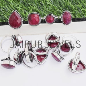 Op de afbeelding: Een verzameling zilveren ringen met rode edelsteen bezettingen. De ringen tonen een verscheidenheid aan edelsteenvormen, waaronder peer, vierkant en ovaal. Alle ringen zijn gezet in zilver en hebben een gepolijste afwerking.