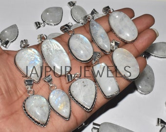 May include: A collection of 12 silver pendants with moonstone gemstones. The pendants are various shapes and sizes, including teardrop, oval, and rectangular. The moonstone gemstones are white with iridescent flashes of color.