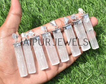 May include: A set of ten white selenite crystal pendants with silver-tone bail settings. The pendants are all different sizes and shapes, but they are all smooth and polished. The pendants are arranged in a row on a hand, with the largest pendant at the top and the smallest pendant at the bottom. The word "JAIPUR JEWELS" is printed on the hand.