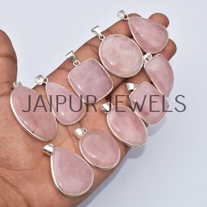May include: A collection of nine rose quartz pendants with silver settings. The pendants are various shapes, including oval, teardrop, and square.