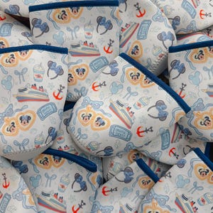 May include: White golf club head covers with a blue trim and a pattern of Mickey and Minnie Mouse, cruise ships, anchors, bows, and cruise tickets. The covers are made of a soft, padded material.