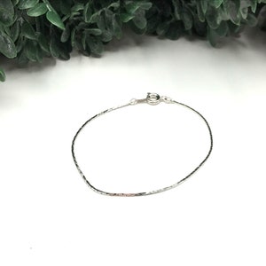 May include: A silver chain bracelet with a lobster clasp.
