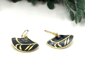 May include: A pair of gold earrings with black enamel and a leaf design.