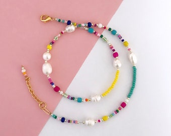 May include: A colorful beaded necklace with white pearl accents. The necklace features a variety of colors, including yellow, pink, blue, green, and red.