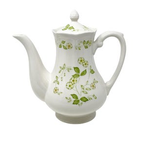 May include: White ceramic teapot with a lid and handle. The teapot is decorated with a floral pattern of green leaves and small white flowers. The spout is long and curved.