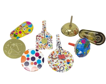 May include: A collection of vintage metal spinning tops and noisemakers featuring colorful circus-themed graphics, polka dots, and clown illustrations. The set includes various shapes such as circular, oval, and shield-like designs with metal stems.