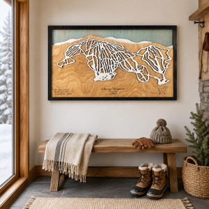 Può includere: Un'opera d'arte murale rettangolare in legno con una mappa bianca tagliata al laser delle piste da sci di Okemo Mountain nel Vermont. La mappa è su uno sfondo in legno naturale con un accento blu, il tutto in una cornice nera con del testo.