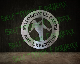 May include: A circular metal sign with the text "MOTORCYCLE PARTS ARE EXPENSIVE" encircling a silhouette of a person on a pole. The sign is silver and set against a dark background with green text.