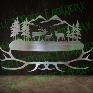 May include: A metal wall art piece featuring a forest scene with deer, trees, and mountains. The design includes a lower section with antler shapes and the text "SELF MADE FABWERX" in a green, stylized font.