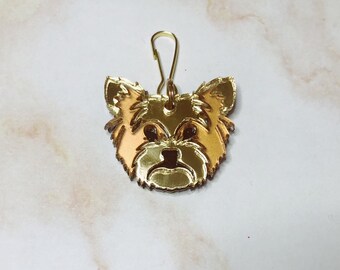 Puede incluir: Encanto de metal dorado con un Yorkshire Terrier con superficie reflectante. El encanto tiene un bucle en la parte superior para sujetarlo a un llavero o bolso.