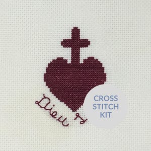 May include: Cross stitch kit featuring a burgundy heart with a cross on top and the text "Dieu est" below. The kit is labeled "Cross Stitch Kit".