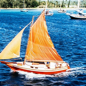 May include: A red and white sailboat with a large orange sail is sailing on a blue body of water. The sailboat has a white cabin and a wooden mast.