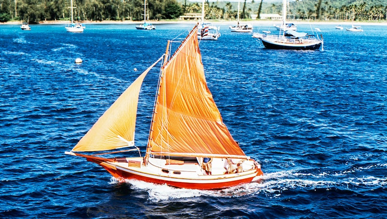 May include: A red and white sailboat with a large orange sail is sailing on a blue body of water. The sailboat has a white cabin and a wooden mast.
