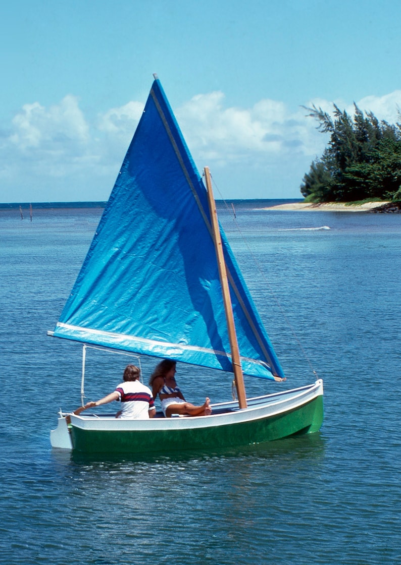 May include: A small sailboat with a blue sail and a green hull is on the water. Two people are sitting in the boat.