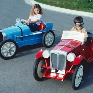 Puede incluir: Dos ni&ntilde;os conduciendo coches de juguete. Una ni&ntilde;a con una camisa blanca conduce un coche de juguete azul, mientras que un ni&ntilde;o con una camisa marr&oacute;n conduce un coche de juguete rojo.