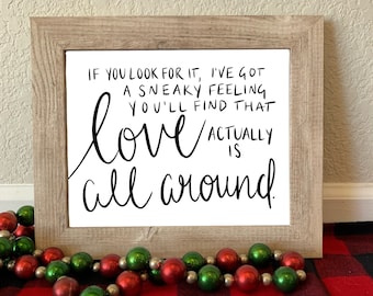 May include: A framed print with a white background and black text that reads "IF YOU LOOK FOR IT, I'VE GOT A SNEAKY FEELING YOU'LL FIND THAT love ACTUALLY IS all around."