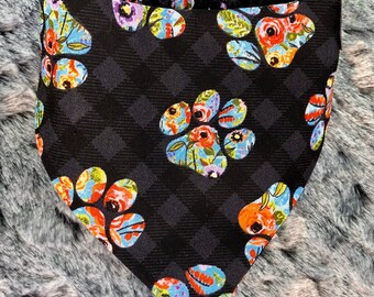 May include: Black bandana with a floral paw print pattern. The bandana has a gathered edge and is made of a soft, comfortable fabric.
