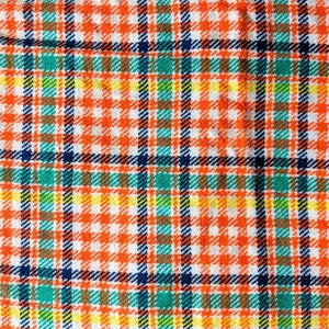 May include: A close-up of a fabric with a plaid pattern in orange, white, blue, green, and yellow.