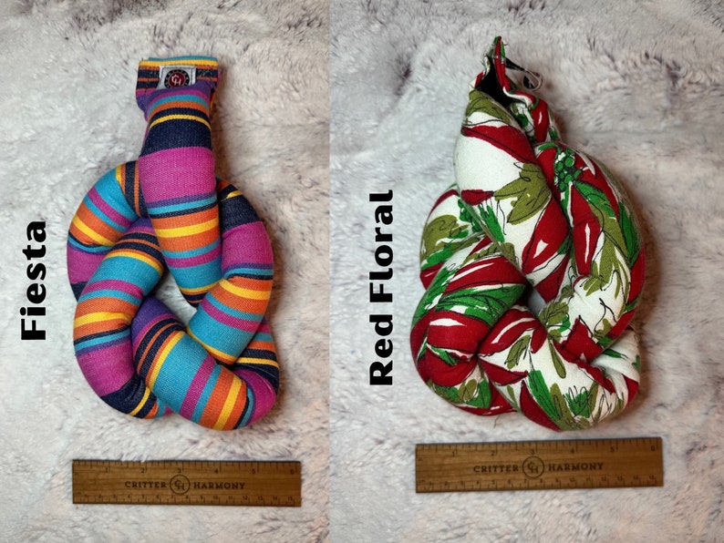 May include: Two knotted dog toys, one with a multi-colored striped pattern and the text "Fiesta" and the other with a red floral pattern and the text "Red Floral".