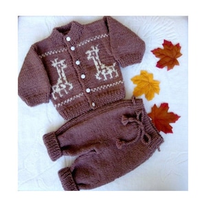 May include: A brown knitted baby sweater and pants set with a white giraffe pattern. The sweater has a button closure.