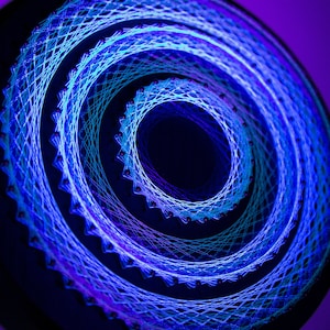 May include: A circular string art piece with concentric circles of blue and purple thread. The circles are woven around nails on a dark background.