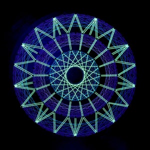Puede incluir: Un diseño circular de arte de cuerda con un esquema de color azul y verde. El diseño presenta una serie de círculos concéntricos con líneas radiantes.