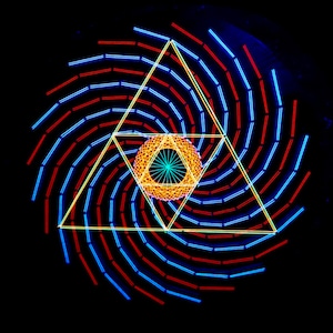 Puede incluir: Un diseño geométrico con un patrón de líneas rojas y azules que giran. El diseño se centra en un triángulo amarillo con un círculo naranja más pequeño en su interior.