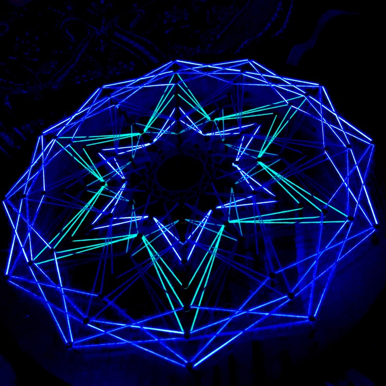 K&ouml;nnte beinhalten: Eine geometrische, beleuchtete Skulptur mit einem komplexen, vielschichtigen Design. Die Struktur besteht aus miteinander verbundenen Linien, die eine sternartige Form bilden. Die Linien leuchten blau und t&uuml;rkis vor einem dunklen Hintergrund.