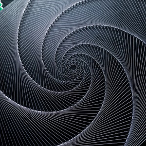 May include: A black and white abstract art piece made with string and nails. The string is arranged in a spiral pattern, creating a sense of depth and movement.