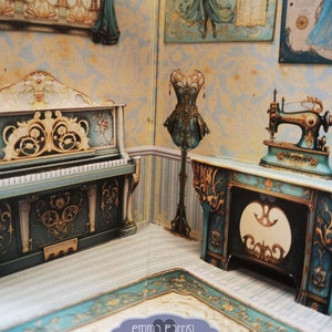 Puede incluir: Un diario emergente imprimible titulado "Blue Fairy Hideaway" con un tutorial incluido. El diario presenta un piano azul y dorado, una m&aacute;quina de coser y un cors&eacute; azul en un soporte. El fondo es un papel tapiz azul claro y dorado con un suelo a rayas.