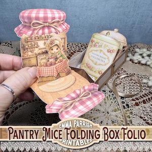 May include: A paper craft folding box folio featuring a die-cut jar shape with a pink gingham lid. The illustration depicts a mouse in a kitchen setting. A rectangular box container holds a card labelled Pantry Blend English Tea with floral accents.
