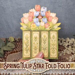 Może przedstawiać: Dekoracyjne papierowe Spring Tulip Star Fold Folio. Folio ma zieloną ramkę z kwiatowymi wzorami i bukiet r&oacute;żowych, brzoskwiniowych i niebieskich tulipan&oacute;w. Widoczny jest tekst "Spring Tulip Star Fold Folio Printables".