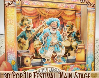 May include: A 3D pop-up card featuring a stage with three whimsical musicians in blue and gold attire. The card is labeled "Part of the Festival Fantasia Series" and "3D Pop Up Festival Main Stage Printables."