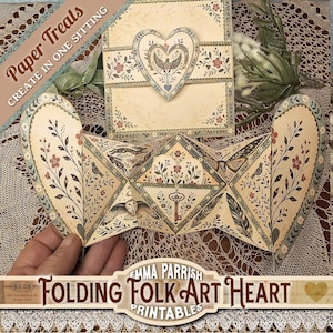 May include: A folded paper heart with floral and bird designs, and the text "Folding Folk Art Heart Printables." The heart is cream-colored with red, green, and brown accents. The image also includes a matching envelope.