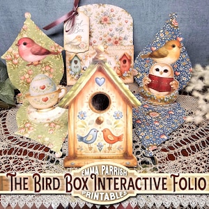May include: A paper craft interactive folio titled The Bird Box by Emma Parrish featuring a central birdhouse cutout, two decorative side panels with bird and floral illustrations, a teacup with an egg, and a tag with a bird graphic.