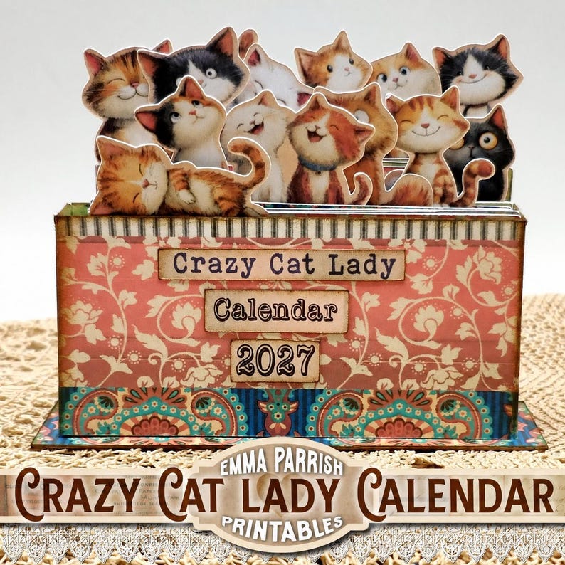 May include: A rectangular desk calendar featuring a pink floral pattern and a blue paisley border. The front displays the text Crazy Cat Lady Calendar 2027. Multiple die-cut illustrations of cartoon cats are attached to the top edge.
