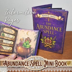 May include: A purple mini book titled The Abundance Spell with gold lettering and illustrations of a pomegranate and cinnamon sticks. The open page displays a copper cauldron, basil leaves, cinnamon sticks, and text labels for ingredients.