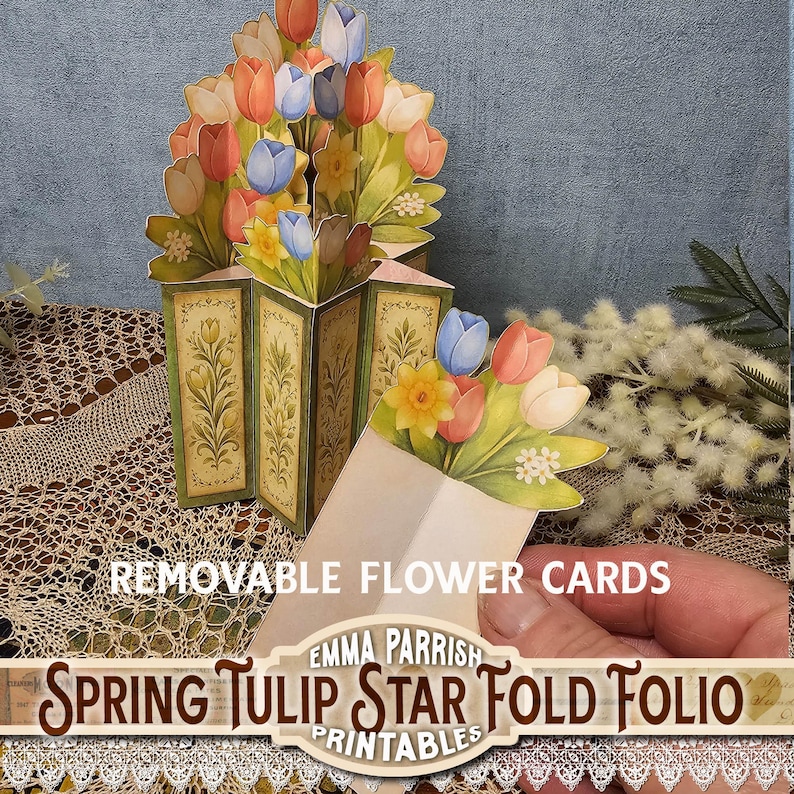 Może przedstawiać: Karta pop-up w kształcie gwiazdy z bukietem tulipan&oacute;w w kolorach r&oacute;żowym, pomarańczowym i niebieskim. Karta zawiera tekst "Spring Tulip Star Fold Folio" i "Removable Flower Cards". Unikalny wz&oacute;r kwiatowy.