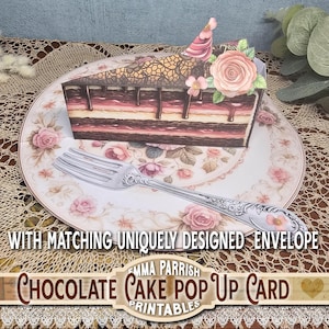 Könnte beinhalten: Ein Stück Schokoladenkuchen-Pop-up-Karte mit einer dekorativen Gabel auf einem floralen Teller. Der Kuchen hat Schichten aus Schokolade und Sahne, gekrönt von einer rosa Blume und einer Partyhütchen. Der Text "Chocolate Cake Pop Up Card Printables".